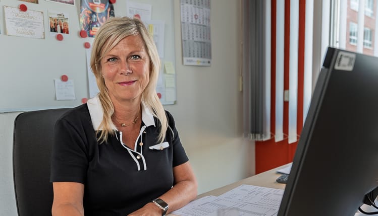 Eine Betriebskostenabrechnerin an ihrem Arbeitsplatz. Sie blickt freundlich in die Kamera.