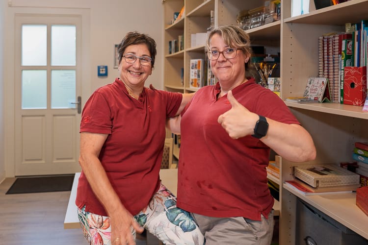 Zwei Pflegekräfte stehen im Spielelager der Tagespflege Reutersagen und lächeln sehr selbstbewußt in die Kamera. 