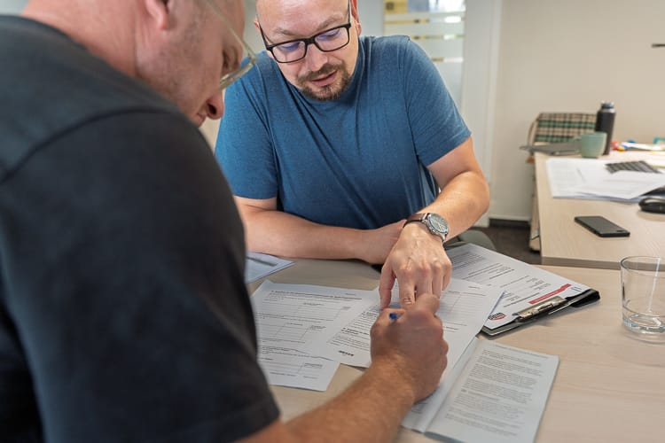 Ein Sozialarbeiter der WIRO hilft einem Klienten beim Ausfüllen eines Formulars.