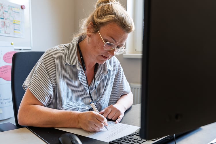Eine Mitarbeiterin eines WIRO-KundenCenter füllt an ihrem Schreibtisch ein Formular aus.  