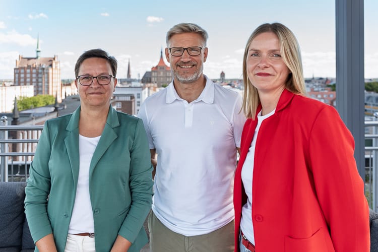 Die drei Mitarbeiter der HR-Abteilung blicken freundlich in die Kamera.