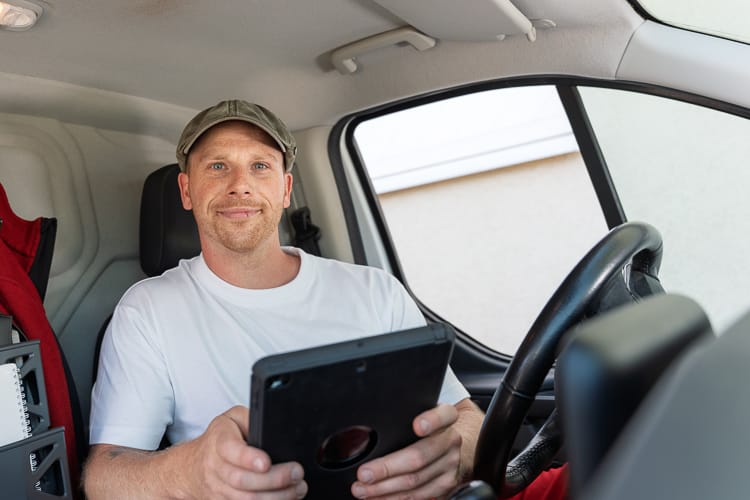 Drei junge WIRO-Mitarbeiter stehen lächelnd vor dem KundenCenter Groß Klein. Der Mann trägt eine rote Latzhose, die Frauen tragen elegante Business-Kleidung.