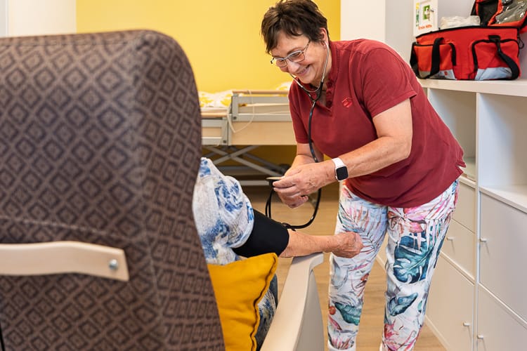 Eine Mitarbeiterin der Tagespflege misst einer Klientin den Blutdruck.