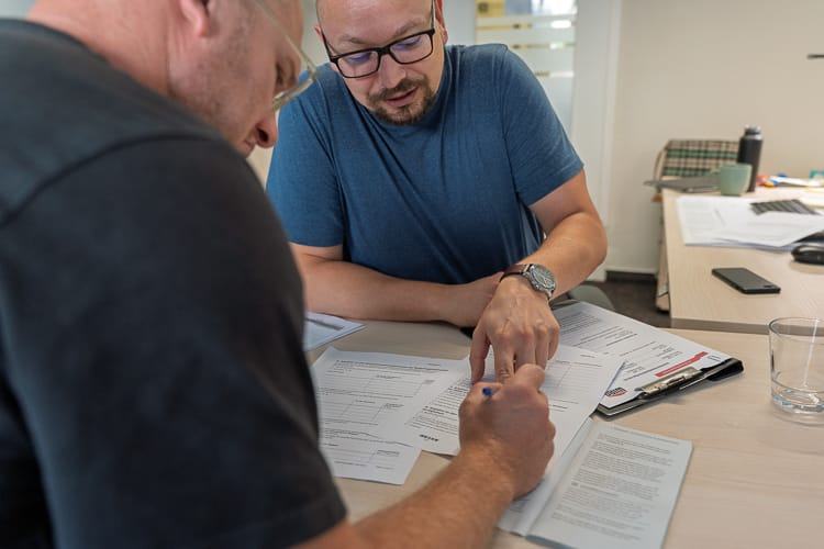 Ein Sozialarbeiter der WIRO hilft einem Klienten beim Ausfüllen eines Formulars. 