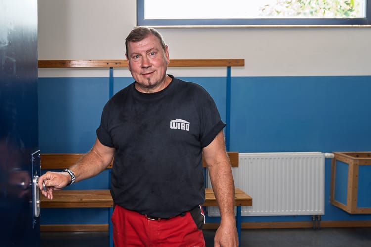 Ein Hallenwart steht in der Tür zu den Umkleidekabinen einer Sportanlage. 