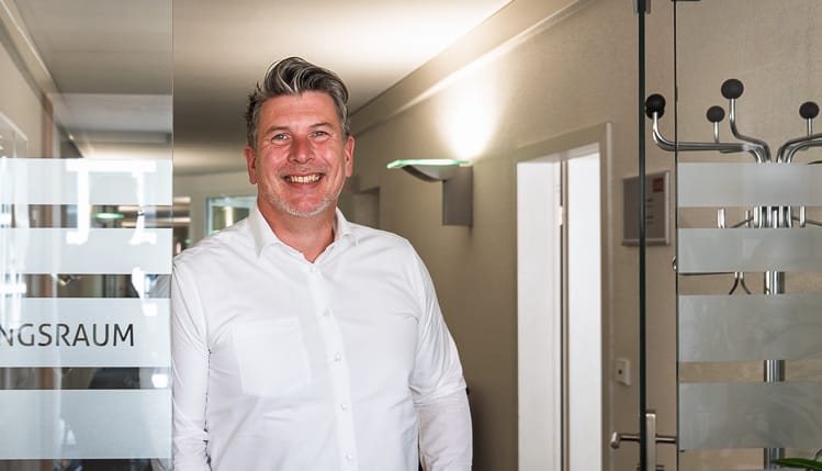 Ein Manager der WIRO lehnt sich an eine Glastüre und blickt freundlich in die Kamera.