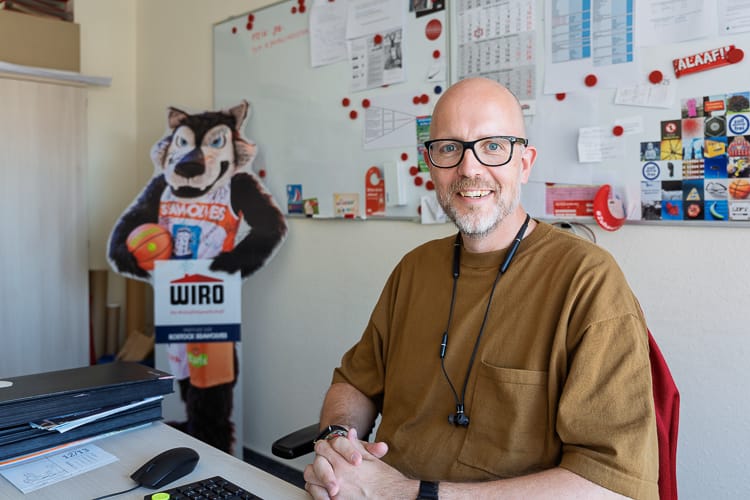 Ein Marketing-Manager in seinem Büro blickt freundlich in die Kamera. 