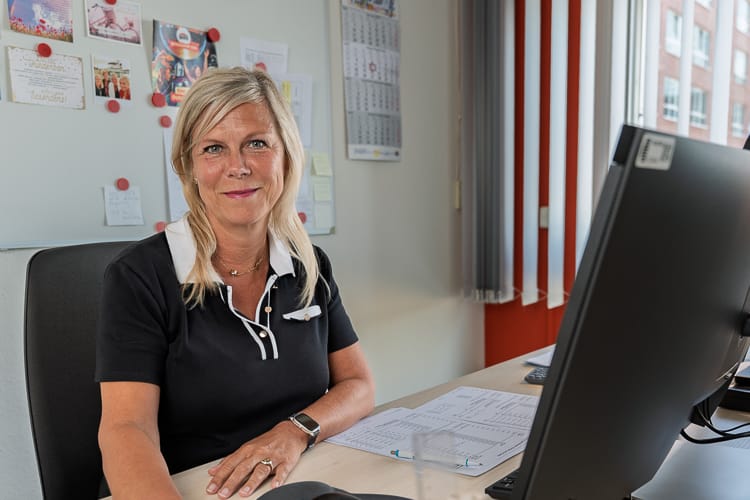 Betriebskostenabrechnerin an ihrem Arbeitsplatz blickt freundlich in die Kamera.