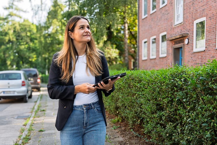 WEG Verwalterin vor einer Wohnanlage.