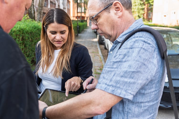 Eine WEG-Verwalterin bespricht etwas mit zwei Baumanagern. 