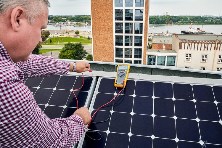 Ein Mitarbeiter der WIRO prüft mit einem Messgerät eine PV-Anlage. 